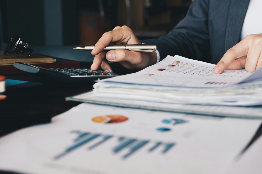 Personne examinant des tableaux et graphiques financiers imprimés sur un bureau
